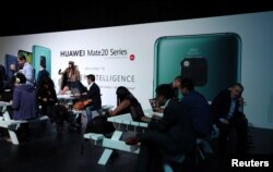 FILE - People attend a Huawei Mate20 smartphone series launch event in London, Britain, Oct. 16, 2018.