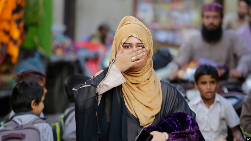 সংসদে প্রতিনিধি কমছেঃ ভারতের আহমেদাবাদে একজন মুসলিম নারী হেঁটে যাওয়ার সময় হাত দিয়ে মুখ ঢাকছেন। 