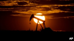 FILE - The sun sets behind an idle pump jack near Karnes City, Texas, April 8, 2020.