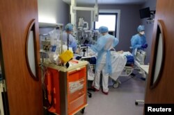 FILE - Medical staff work in the intensive care unit where COVID-19 patients are treated at Cambrai hospital, France, March 25, 2021.