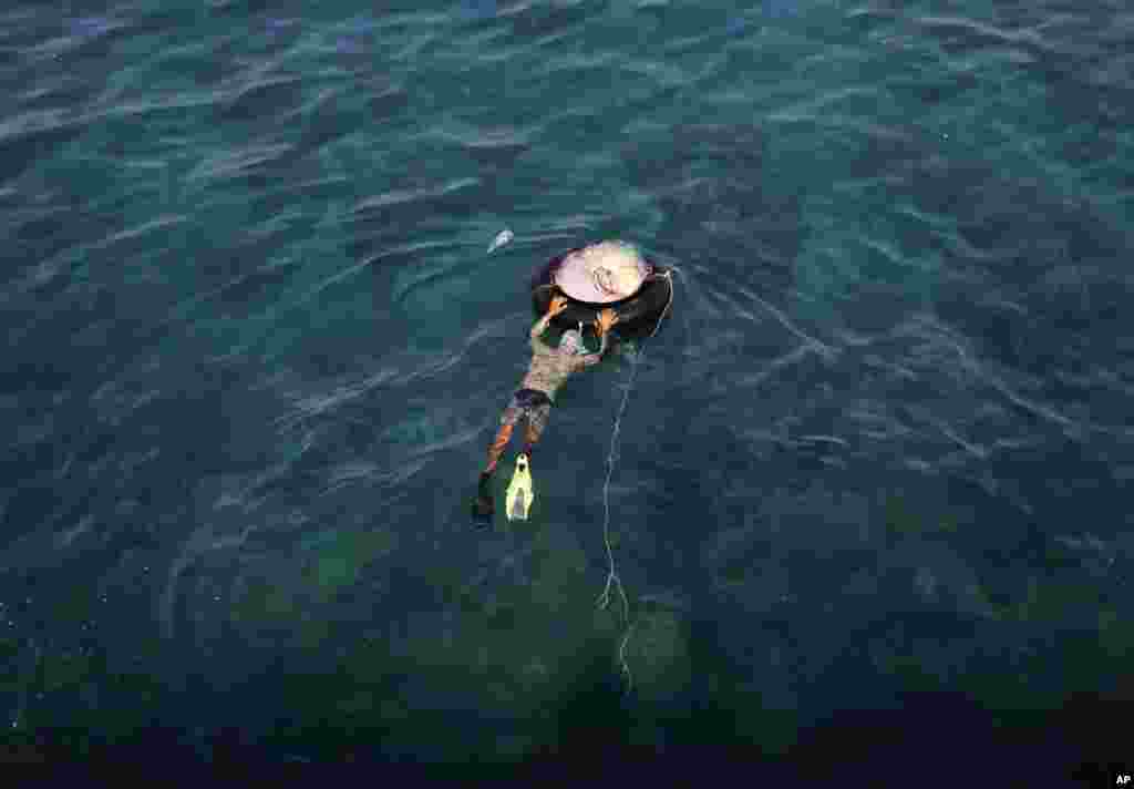 A Lebanese diver pushes his fishing net inside an inner tube, as he prepares to fish in the Mediterranean Sea off the Corniche, or waterfront promenade, in Beirut, Lebanon.