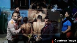 Men arrested at the Bab el-Bahr public bath house are herded into a police van, Dec. 7, 2014. Egyptian journalist Mona Iraqi appears at right, with camera phone. Screenshot from Mona Iraq's Facebook page, courtesy Scott Long