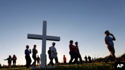 Para peserta membagikan salib kayu pada saat mereka tiba di acara doa bersama untuk para korban di SMU Marjory Stoneman Douglas, di Parkland, Florida, 15 Februari 2018.