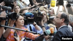 France's President Francois Hollande (R) talks to the media as he arrives at an informal EU leaders summit in Brussels, May 23, 2012.