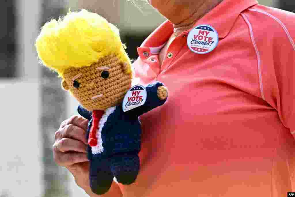 A supporter of former President and Republican presidential candidate Donald Trump holds a knitted doll of Trump outside the polling station at Mandel Recreation Centre in Palm Beach, Florida, Nov. 5, 2024.