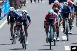 La cubana Arlenis Sierra, al frente a la derecha, y la venezolana Lilibeth Chacón, al frente a la izquierda, compiten en la final de la carrera de ciclismo en ruta femenino en los Juegos Centroamericanos y del Caribe en San Salvador, El Salvador, el viernes 7 de julio de 2023. (Foto AP/Arnulfo Franco )