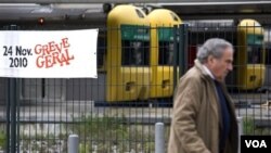 Seorang pria berjalan melewati sebuah spanduk bertuliskan 'Aksi Mogok Umum' dipasang di depan sebuah stasiun kereta dalam kota di Lisabon, Portugal.