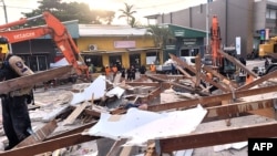 This handout photo taken and released Dec. 20, 2024, by the Australian Department of Foreign Affairs and Trade shows Australian rescue workers at the site of a collapsed building after an earthquake struck Port Vila, Vanuatu. 