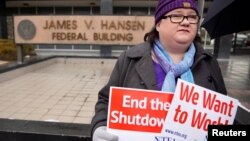 A U.S. Internal Revenue Services employee holds signs in front of the federal building at a rally against the U.S. federal government shutdown, in Ogden, Utah, Jan. 10, 2019.