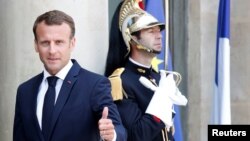 FILE - French President Emmanuel Macron welcomes a guest before a meeting at the Elysee Palace in Paris, France, May 23, 2018. 