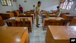 Anggota staf sekolah membersihkan ruang kelas setelah sekolah ditutup untuk mencegah penyebaran virus corona di Solo, Jawa Tengah, 16 Maret 2020. (Foto: AP)