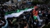 Warga Palestina berbaris membawa bendera nasional mereka dalam unjuk rasa memperingati 75 tahun apa yang mereka sebut "Nakba," atau "malapetaka", di Kota Ramallah, Tepi Barat, Senin, 15 Mei 2023. (Foto: AP)