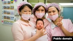 A group of nurses holds a newborn baby. 