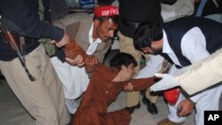 People try to comfort a boy who lost his family member, at a local hospital in Peshawar, Pakistan, Monday, Feb 27, 2012.