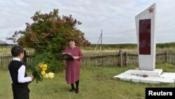 Ravil Izhmukhametov, 9, and teacher Uminur Kuchukova, 61, attend the ceremony on the first day of the new school year next to a WWII monument in the village of Sibilyakovo, Omsk region, Russia, September 2, 2019. 