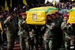 Anggota Hizbullah membawa peti jenazah dua rekan mereka yang tewas pada hari Rabu ketika sebuah bom genggam meledak, selama prosesi pemakaman di pinggiran selatan Beirut, Kamis (19/9).