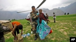 Indian army soldier helps an injured Indian pilgrim after she was rescued from the higher reaches of mountains, at a makeshift helipad at Joshimath, in northern Indian state of Uttarakhand, June 24, 2013.