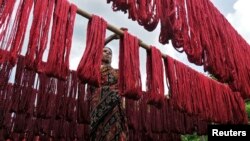 FILE - A woman hangs dyed yarn to dry at a textile mill in India, June 11, 2010.