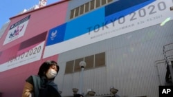 In this Feb. 24, 2021, file photo, people walk past posters to promote the Olympic Games scheduled to start in the summer in Tokyo. (AP Photo/Koji Sasahara, File)