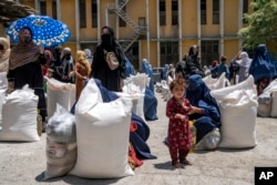 FILE - Afghan women receive food from a humanitarian aid group, in Kabul, Afghanistan, Sunday, May 28, 2023. (AP Photo/Ebrahim Noroozi)