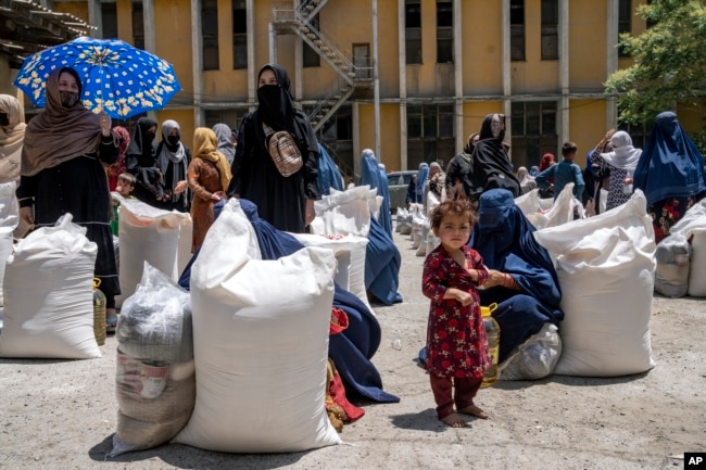 FILE - Afghan women receive food from a humanitarian aid group, in Kabul, Afghanistan, Sunday, May 28, 2023. (AP Photo/Ebrahim Noroozi)