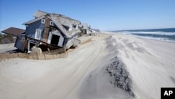 FILE - Homes severely damaged by Superstorm Sandy are seen along the beach in Mantoloking, N.J., April 25, 2013. Mantoloking and Ocean City, N.J., planned to go to court to seize control of narrow strips of beachfront land from property owners blocking a desperately needed protective dune system along New Jersey's 127-mile coast.