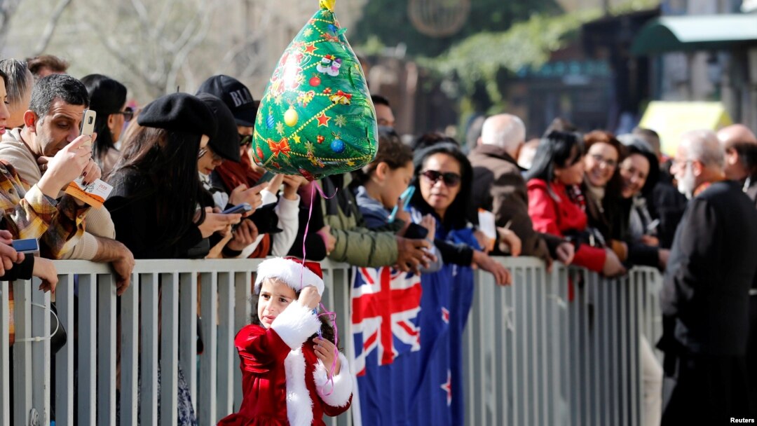 Seorang anak perempuan mengenakan pakaian Sinterklas dan memegang balon mengikuti perayaan Natal di Lapangan Palungan (Manger Square), Bethlehem, 24 Desember 2019. (Foto: Reuters)