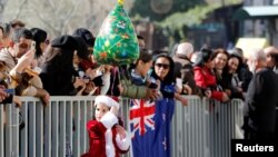 Seorang anak perempuan mengenakan pakaian Sinterklas dan memegang balon mengikuti perayaan Natal di Lapangan Palungan (Manger Square), Bethlehem, 24 Desember 2019. (Foto: Reuters)