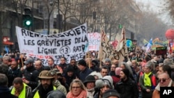 Demonstrators march with banners during a protest against pension reform plans in Paris, Dec. 28, 2019.