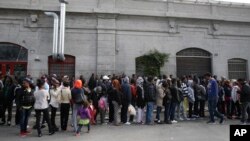 Des migrants attendent en file d’entrer dans le réfectoire dans un centre de réfugiés à Milan, Italie, 21 octobre 2016.