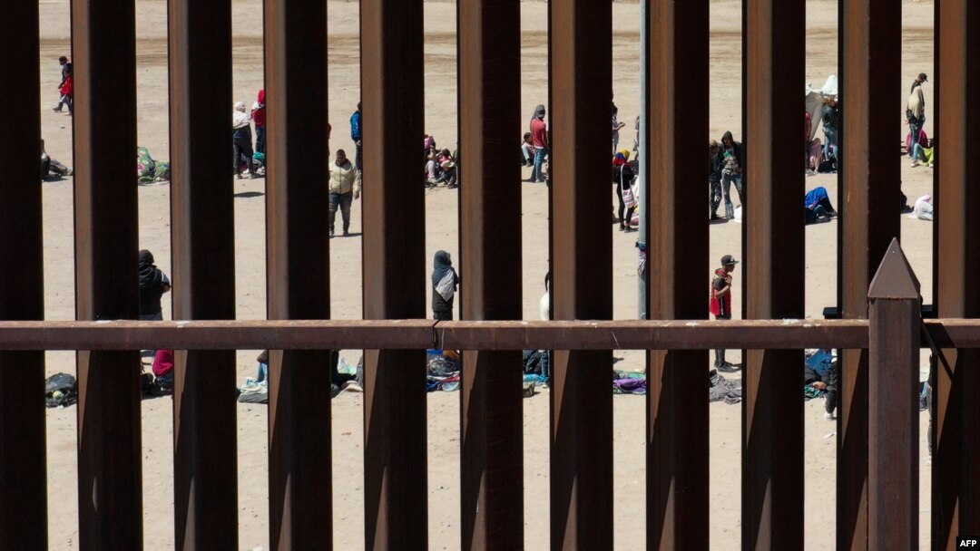 Para migran menunggu di sepanjang tembok perbatasan untuk menyerahkan diri kepada petugas patroli Dinas Bea Cukai dan Perlindungan Perbatasan AS (CBP) di El Paso, Texas, 11 Mei 2023. (Foto: Patrick T. Fallon/AFP)