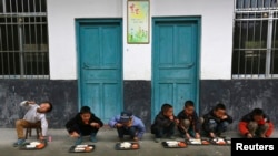 FILE - Students have lunch outdoors at a primary school in Tongguan village, Liping county, Guizhou province, November 24, 2014.