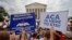 Supporters of the Affordable Care Act hold up signs as the opinion for health care is reported outside of the Supreme Court in Washington, June 25, 2015. 
