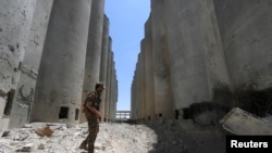 ARSIP – Pejuang Syrian Democratic Forces (SDF) berjalan di antara silo dan pabrik di Manbij setelah SDF mengambil alih fasilitas tersebut (1/7). Kegubernuran Aleppo, Suriah. (foto: REUTERS/Rodi Said)