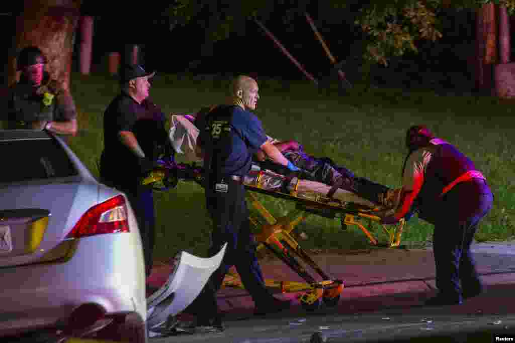 Emergency personnel carry a victim from a car crash into an ambulance after protests against the shooting of Michael Brown turned violent near Ferguson, Missouri, Aug. 17, 2014.