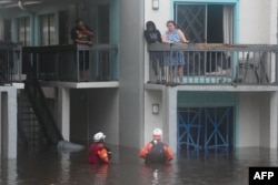 Regu penyelamat berupaya menyelamatkan warga yang terdampak banjir akibat Badai Milton di kompleks apartemen lantai dua di Clearwater, Florida, 10 Oktober 2024. (Bryan R. SMITH / AFP)