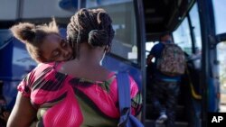 FILE - A woman and child prepare to board a bus to San Antonio moments after a group of migrants, many from Haiti, were released from custody upon crossing the Texas-Mexico border in search of asylum in Del Rio, Texas, Sept. 22, 2021.