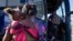 FILE - A woman and child prepare to board a bus to San Antonio moments after a group of migrants, many from Haiti, were released from custody upon crossing the Texas-Mexico border in search of asylum in Del Rio, Texas, Sept. 22, 2021.