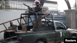 Pakistani security forces stand guard at the site of a deadly blast by four Taliban suicide bombers in Bannu, Pakistan, December 10, 2012.