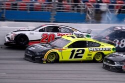 El ganador Ryan Blaney (12) se acerca a la línea de meta cuando el piloto Erik Jones (20) se estrella al final de la carrera de la Copa NASCAR en Talladega Superspeedway en Talladega Ala. Lunes 22 de junio de 2020.