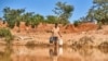 Seorang pria mengambil air di sebuah kolam untuk ternak-ternaknya di Matobo, Matabeleland, 10 Mei 2024. (Foto: Zinyange Auntony/AFP)