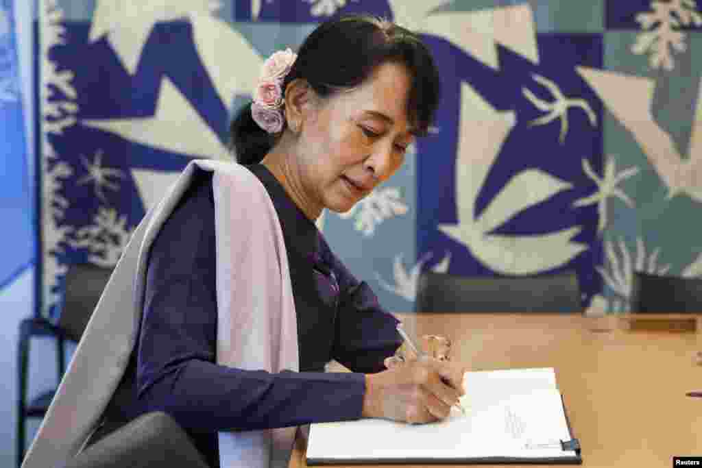 ທ່ານນາງ Aung San Suu Kyi ລົງນາມໃນສະມຸດຕ້ອນຮັບແຂກ ຂອງເລຂາທິການໃຫຍ່ອົງການສະຫະປະ ຊາຊາດ ທ່ານ&nbsp; Ban Ki-Moon ຢູ່ທີ່ສໍານັກງານອົງການສະຫະປະຊາຊາດ ທີ່ New York, ວັນທີ 21 ກັນຍາ 2012. 