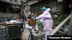 A villager receives a dose of COVISHIELD vaccine during a door-to-door vaccination and testing drive at Uttar Batora Island, India, June 21, 2021.