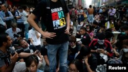 Demonstran pro-demokrasi memblokir bagian sebuah jalan setelah polisi membongkar barikade di tempat protes di distrik perbelanjaan Mongkok di Hong Kong (17/10). (Reuters/Carlos Barria)