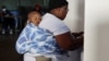 (FILE) A woman with a child votes at Mponegele Primary School during the South African elections in Seshego, Limpopo Province, South Africa May 29, 2024.