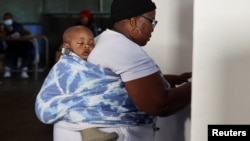 (FILE) A woman with a child votes at Mponegele Primary School during the South African elections in Seshego, Limpopo Province, South Africa May 29, 2024.