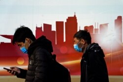 Personas con mascarilla pasan frente a un perfil de rascacielos en Beijing, el domingo 6 de diciembre de 2020, Gobiernos provinciales chinos han presentado órdenes para una vacuna experimental del país.