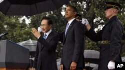 U.S. President Barack Obama and South Korean President Lee Myung-bak (L) are sheltered from the rain by U.S. military personnel (R) holding umbrellas on the South Lawn of the White House in Washington, October 13, 2011.