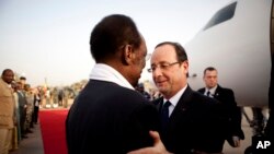 ປະທານາທິບໍດີຝຣັ່ງ ທ່ານ Francois Hollande (ກາງຂວາ) ຖືກຕ້ອນຮັບໂດຍປະທານາທິບໍດີມາລີ ທ່ານ Dioncounda Traore ຂະນະທີ່ທ່ານເດີນທາງໄປເຖິງເມືອງ Sevare ໃນພາກກາງຂອງປະເທດມາລີ ກ່ອນຈະໄປຢ້ຽມເມືອງ Timbuktu (2 ກຸມພາ 2013)