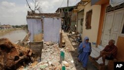FILE - A woman walks past a partly demolished houses ahead of an eviction by the government in Jakarta, Indonesia, Sept. 20, 2016. 
